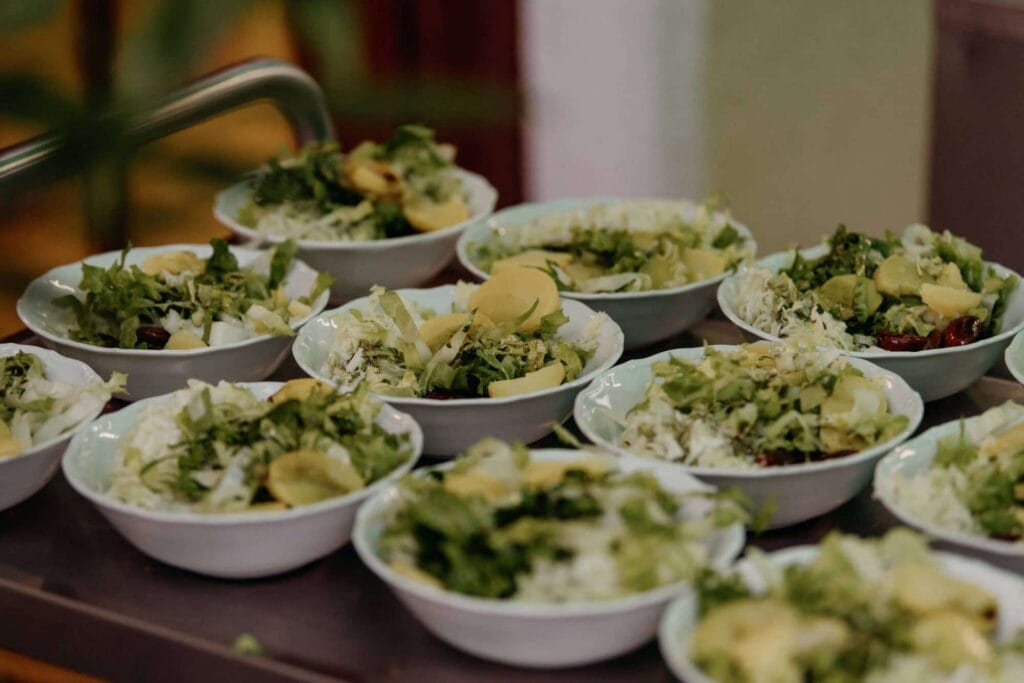 Verschiedene grüne Salate in weißen Schalen, ideal für Veranstaltungen.