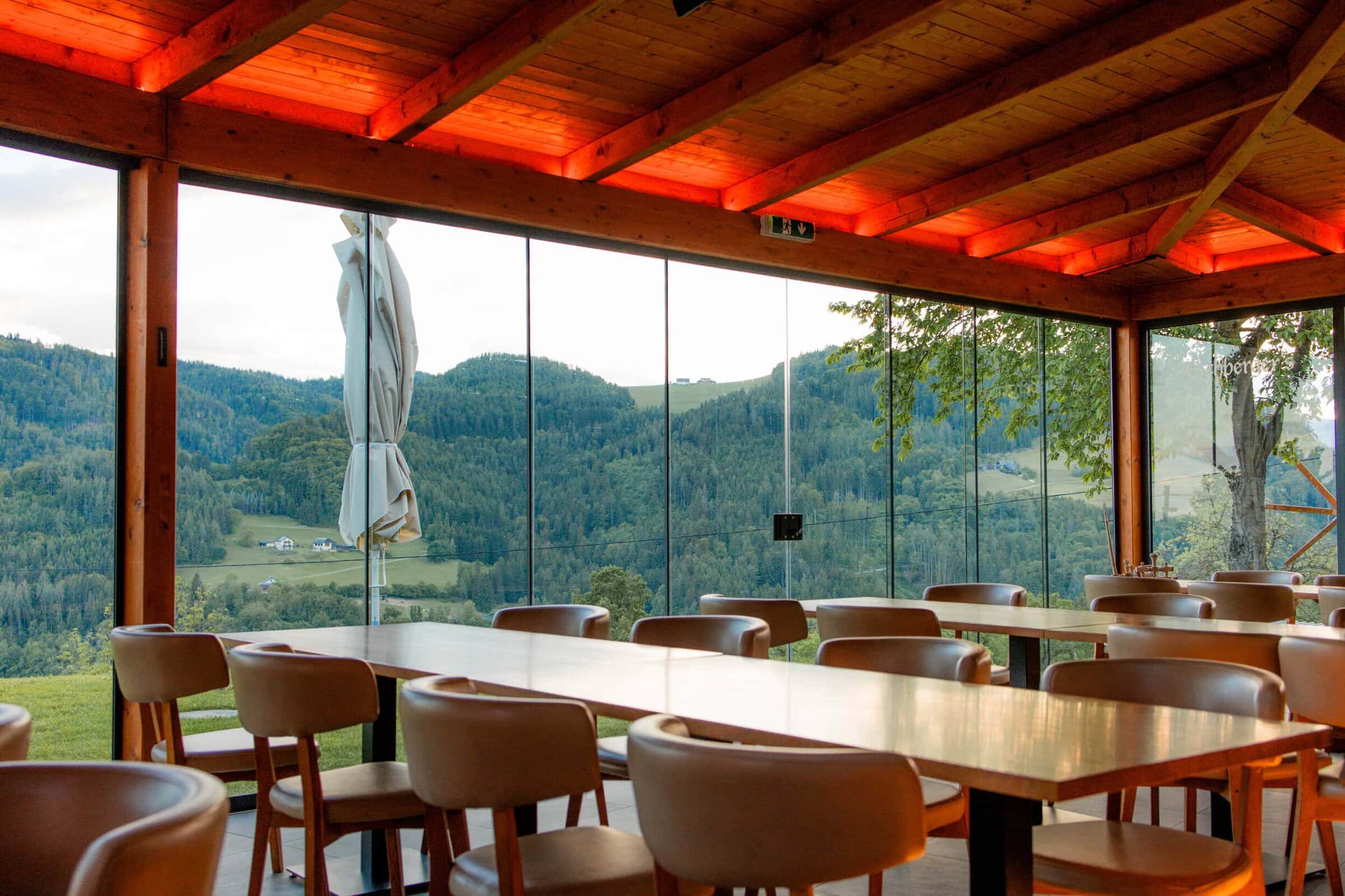 Innenansicht eines Restaurants mit Blick auf die Natur und Berge.