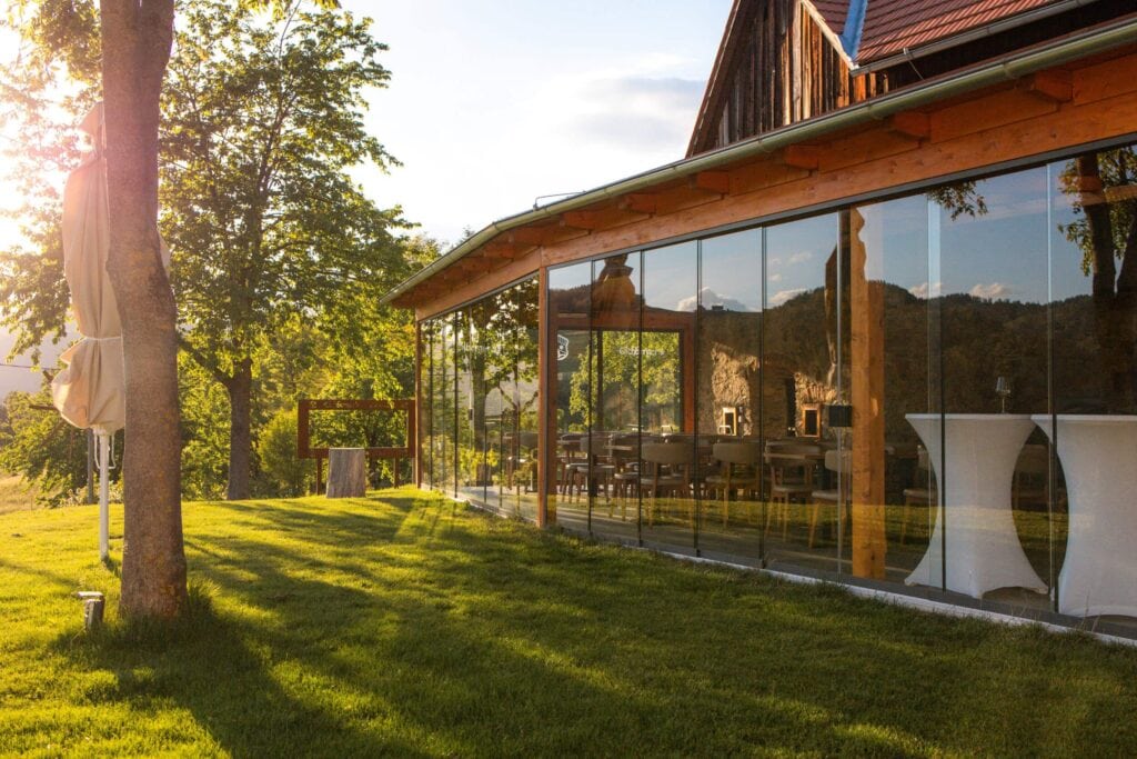 Moderne Eventlocation mit Glasfassade, umgeben von Natur, ideal für Veranstaltungen.