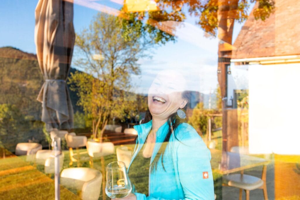 Frau mit Glas Wein bei Gartenparty, lachend, im Freien, Herbst.